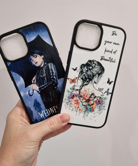 Hand holding two iPhone 15 cases with custom designs, one featuring a dark-themed character and the other a colorful artistic floral design.